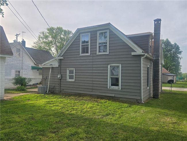 Rear view of property featuring a chimney, a lawn, and central air condition unit | Image 30