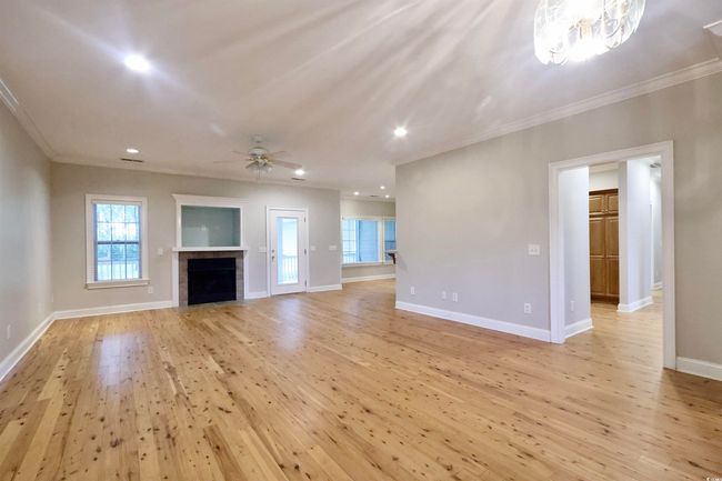 Unfurnished living room with ornamental molding, light wood finished floors, a ceiling fan, recessed lighting, and a chandelier | Image 4