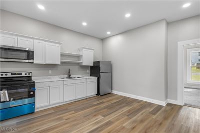 Kitchen with light hardwood / wood-style floors, stainless steel appliances, sink, and white cabinetry | Image 3