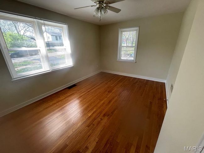 Empty room with visible vents, baseboards, wood finished floors, and ceiling fan | Image 22