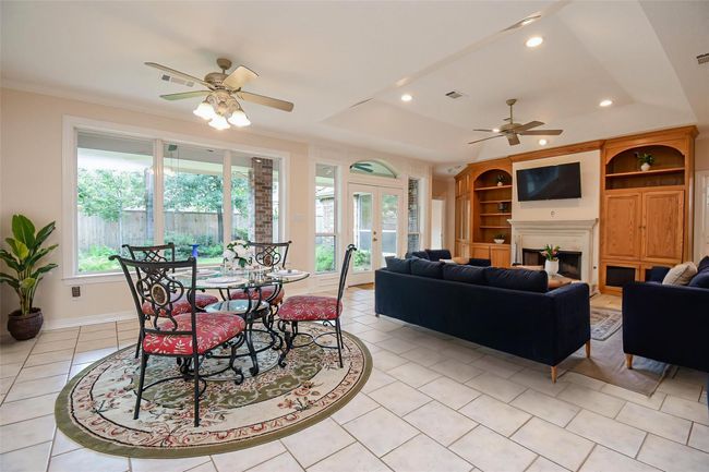 This bright bedroom features high vaulted ceilings, large arched windows with a view of greenery, and an adjoining en-suite bathroom. It has neutral-colored walls and carpet, with a ceiling fan for comfort. *Virtually staged | Image 26