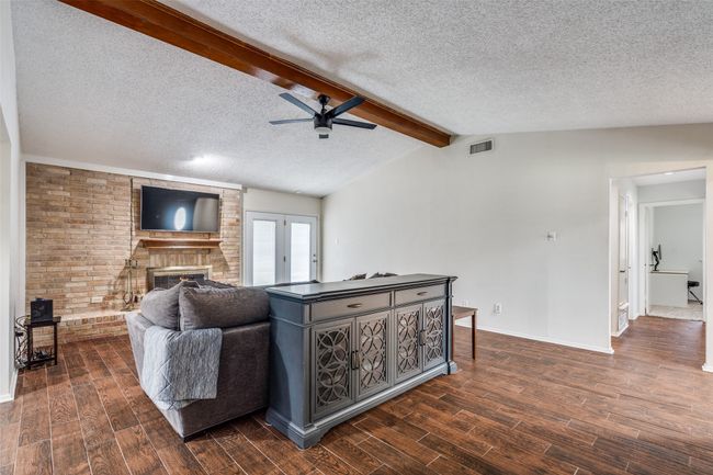 Living area with a textured ceiling, a ceiling fan, dark wood-style floors, and a fireplace | Image 7