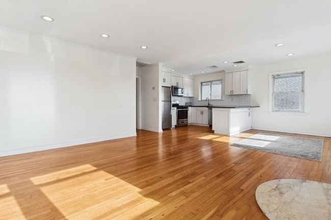 Unfurnished living room featuring a sink, light wood-type flooring, baseboards, recessed lighting, and visible vents | Image 6