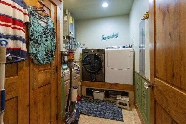 Laundry room featuring washing machine and clothes dryer, light tile patterned floors, tankless water heater, recessed lighting, and electric panel | Image 25