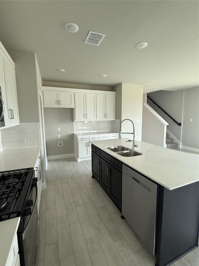 Kitchen with dishwashing machine, stove, white cabinets, backsplash, and light stone counters | Image 8