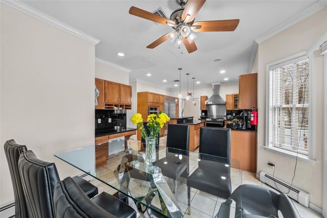 Dining room featuring light tile patterned floors, baseboard heating, crown molding, and ceiling fan | Image 9