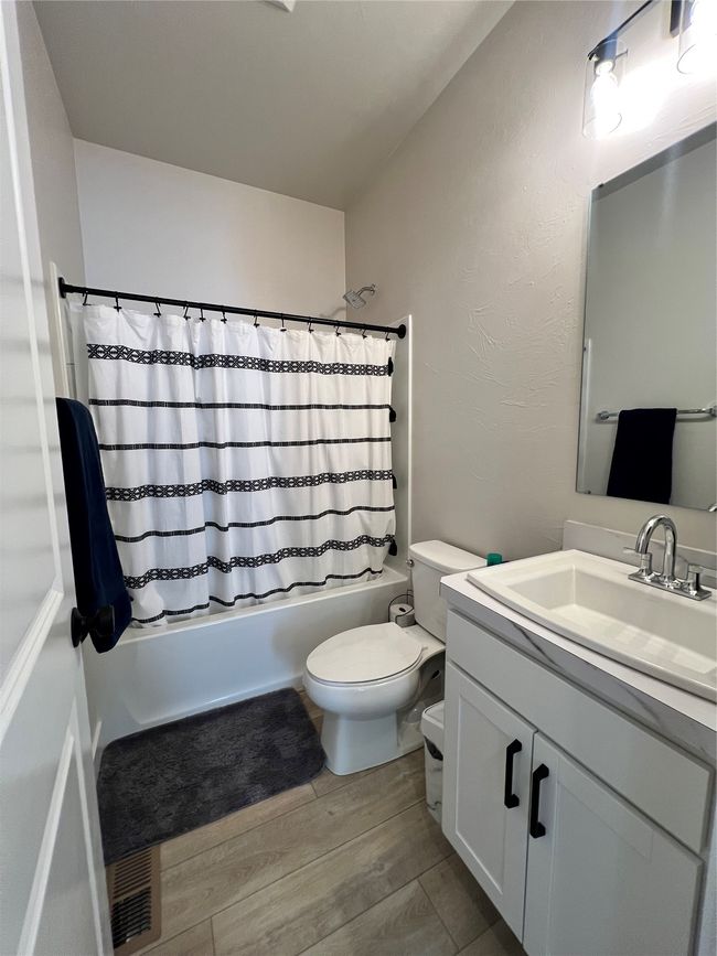 Full bath featuring vanity, toilet, shower / bath combo, and wood finished floors | Image 18