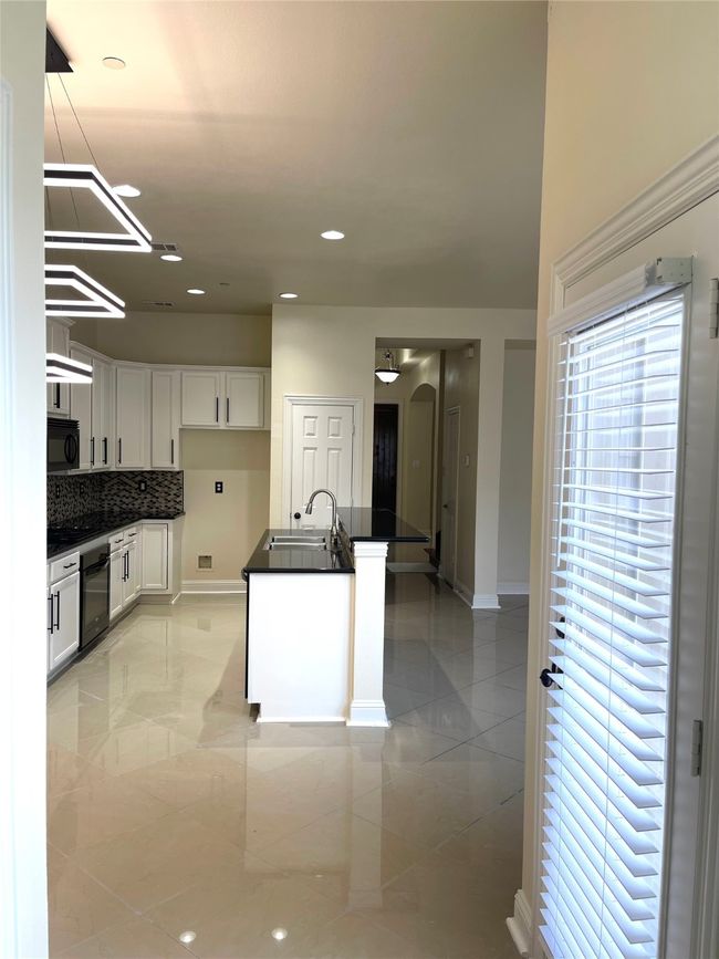 Kitchen with black microwave, dark countertops, white cabinets, oven, and arched walkways | Image 10