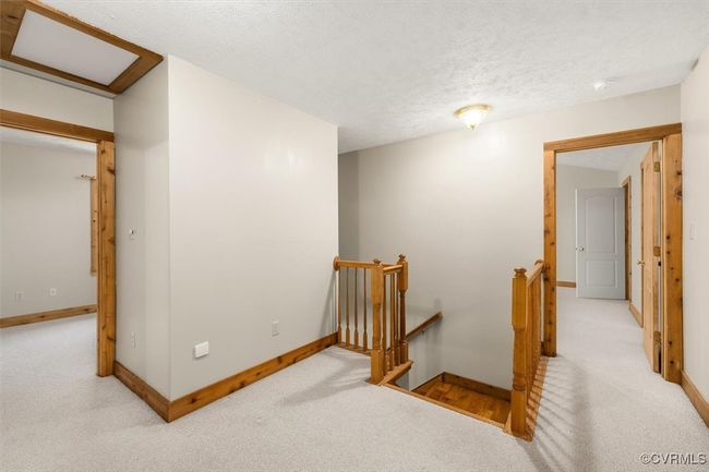 Hall featuring a textured ceiling and light carpet | Image 42