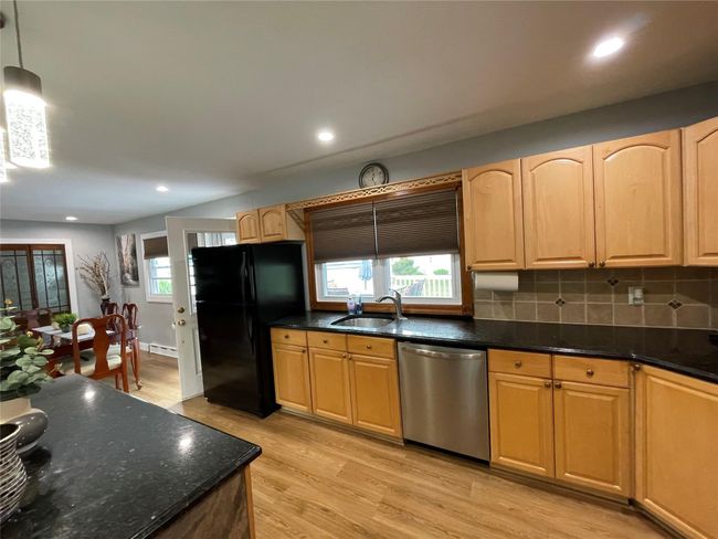 Kitchen with stainless steel dishwasher, freestanding refrigerator, a sink, light wood-style floors, and healthy amount of natural light | Image 16