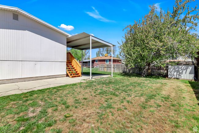 View of yard featuring a patio area, an outdoor structure, stairs, a storage unit, and fence | Image 27