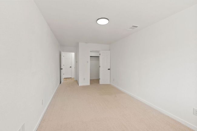 Bedroom 2 featuring a walk in closet, light carpet, baseboards, and visible vents | Image 21