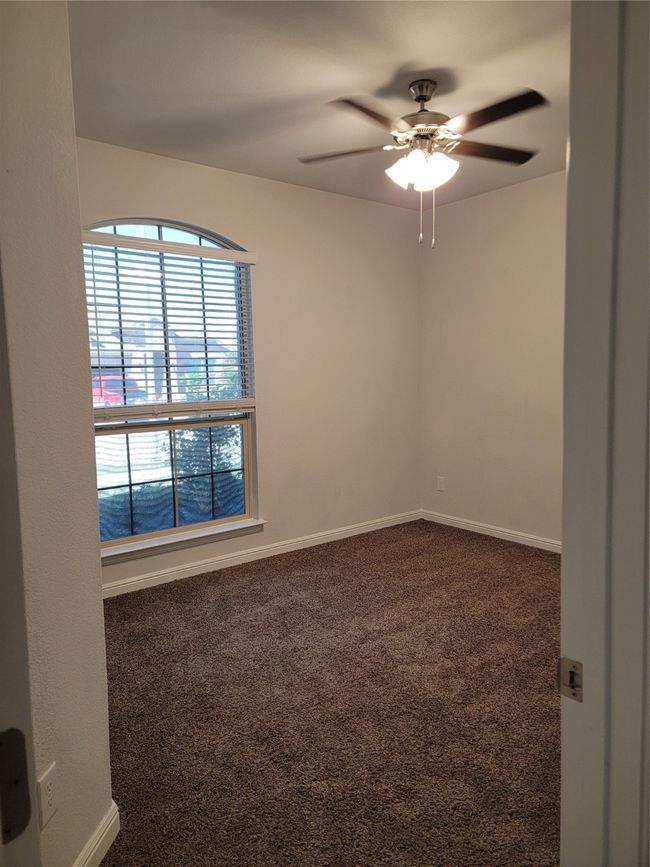 Empty room featuring dark colored carpet, ceiling fan, and baseboards | Image 17