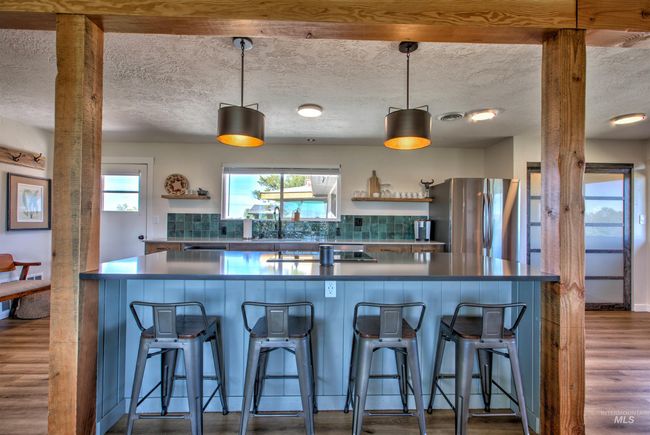 Kitchen with freestanding refrigerator, open shelves, dark wood finished floors, dark countertops, and a textured ceiling | Image 8