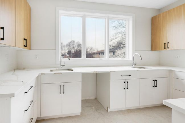Kitchen featuring white cabinets, light brown cabinets, light stone counters, and sink | Image 23