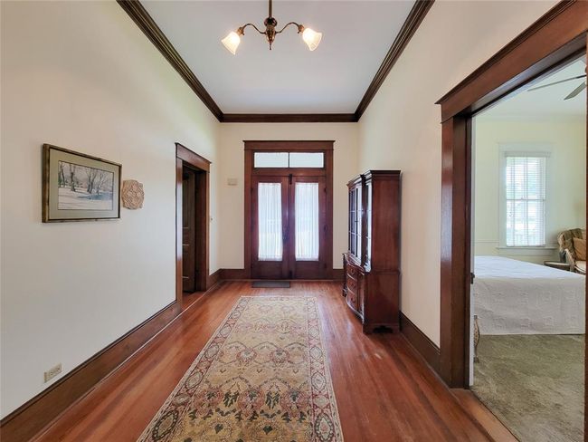 Step into a stunning foyer with elegant antique hardwood floors, timeless architecture, soaring 11-foot ceilings, and original brass chandeliers. | Image 7