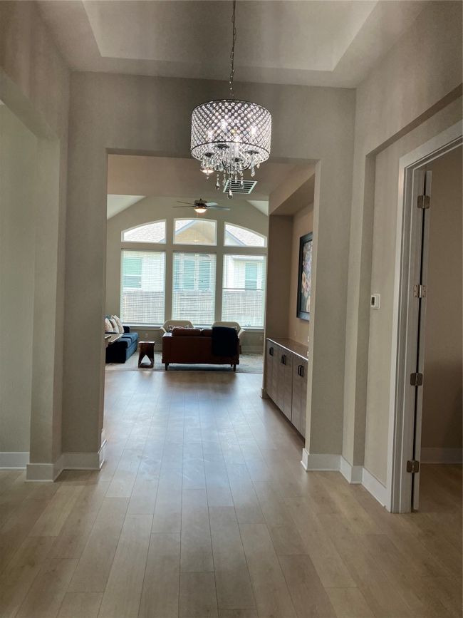 Hallway featuring a chandelier, light wood-style flooring, baseboards, and a raised ceiling | Image 4