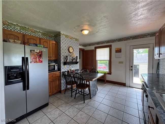 Kitchen featuring appliances with stainless steel finishes, a textured ceiling, baseboards, brown cabinets, and dark countertops | Image 11