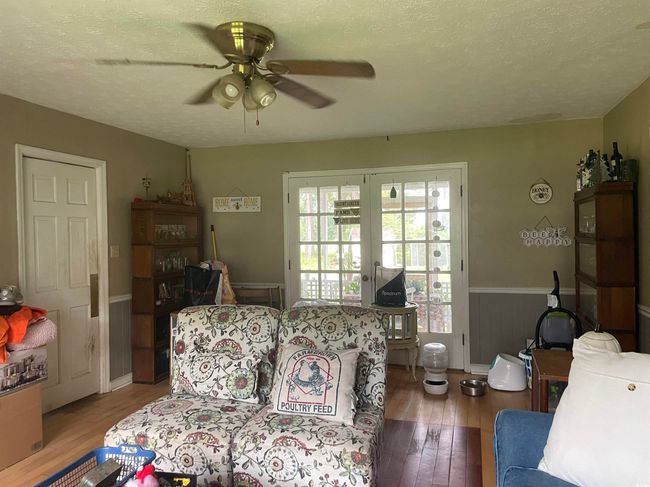Living room with a ceiling fan, wood finished floors, a textured ceiling, and a wainscoted wall | Image 10