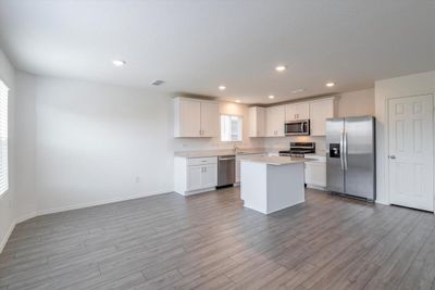 Kitchen with appliances with stainless steel finishes, sink, light wood-type flooring, a center island, and white cabinetry | Image 3