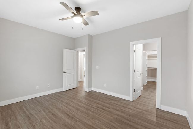 Unfurnished bedroom with wood finished floors, baseboards, a spacious closet, and a ceiling fan | Image 19