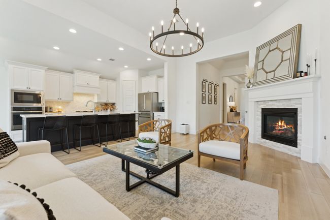 Living room featuring light wood finished floors, recessed lighting, a chandelier, a stone fireplace, and baseboards | Image 4