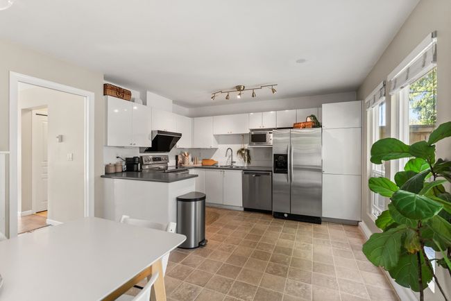 Kitchen featuring stainless steel appliances, dark countertops, white cabinets, and a sink | Image 18