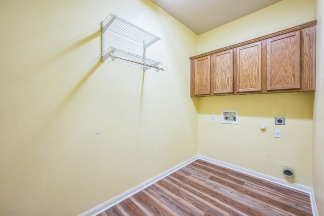 Laundry room with wood finished floors, hookup for a washing machine, hookup for an electric dryer, cabinet space, and baseboards | Image 21