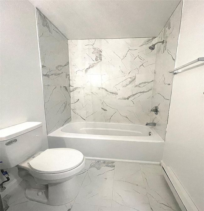 Bathroom with bathing tub / shower combination, toilet, marble finish floor, baseboards, and baseboard heating | Image 13