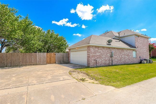 View of side of property with brick siding, driveway, an attached garage, central AC unit, and roof with shingles | Image 16