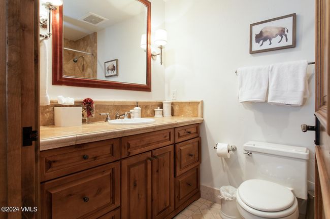 Rustic charm meets practical design in this stylish guest bath—featuring custom cabinetry, a walk-in shower, and warm stone finishes throughout. | Image 15