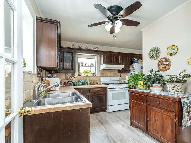 Kitchen with under cabinet range hood, tasteful backsplash, a sink, and white range with gas cooktop | Image 6