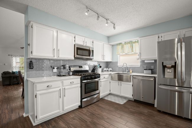 The kitchen feels like a breath of fresh air with quartz countertops, white cabinetry, and stainless steel appliances that blend seamlessly, making the space feel effortlessly modern | Image 14
