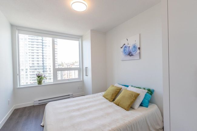 Bedroom featuring dark wood finished floors, a baseboard radiator, baseboards, and multiple windows | Image 6