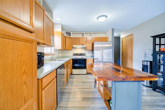 Kitchen featuring under cabinet range hood, appliances with ample counter space and wood flooring | Image 13