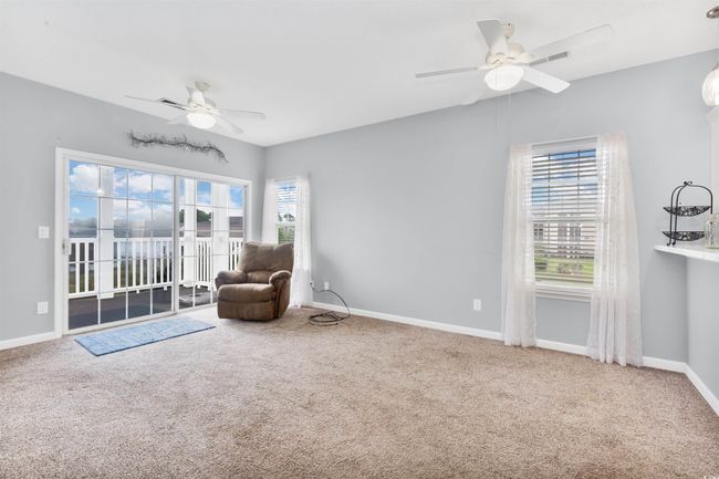 Sitting room with a ceiling fan, carpet floors, and baseboards | Image 8