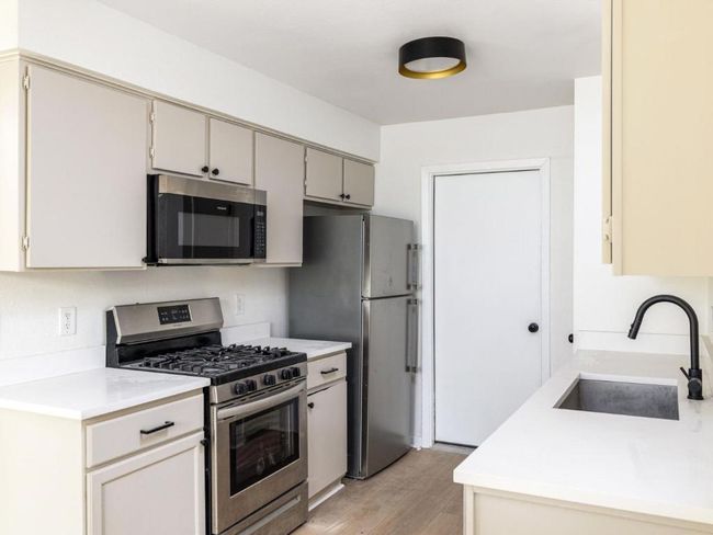 Kitchen with stainless steel appliances, a sink, light wood finished floors, and light countertops | Image 11