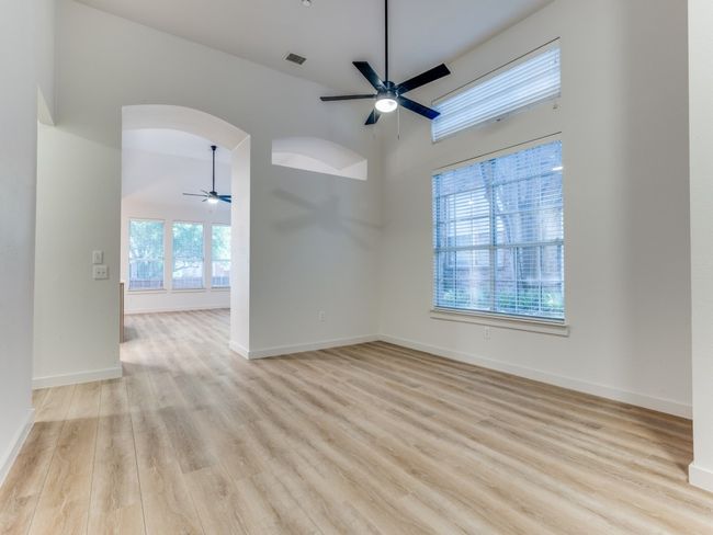 Unfurnished room featuring a ceiling fan, arched walkways, healthy amount of natural light, and a high ceiling | Image 5