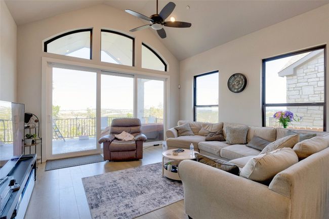 Living room featuring high vaulted ceiling, light wood-style flooring, and ceiling fan | Image 24
