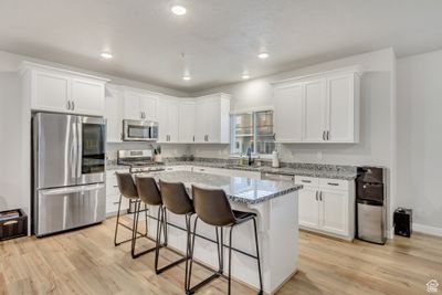 Kitchen featuring a kitchen island, appliances with stainless steel finishes, a breakfast bar area, and light hardwood / wood-style floors | Image 1