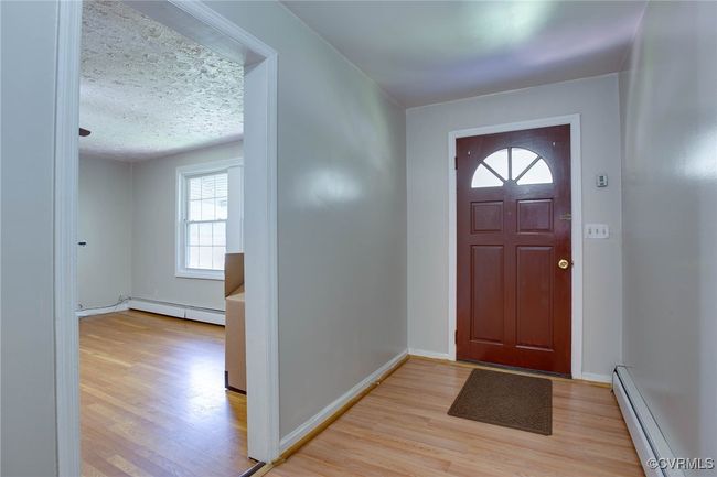 Foyer entrance featuring a baseboard heating unit, a textured ceiling, and light hardwood / wood-style flooring | Image 7
