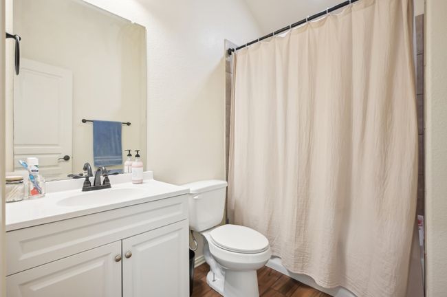 Bathroom with a shower with shower curtain, vanity, toilet, and wood finished floors | Image 30