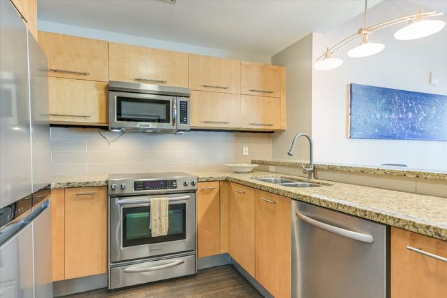 Kitchen featuring tasteful backsplash, light stone countertops, stainless steel appliances, and a sink | Image 8