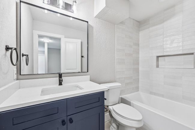 Bathroom with a textured wall, toilet, vanity, and bathtub / shower combination | Image 18