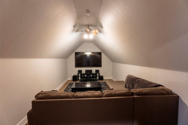 Home theater room with lofted ceiling, ceiling fan, and a textured ceiling | Image 29