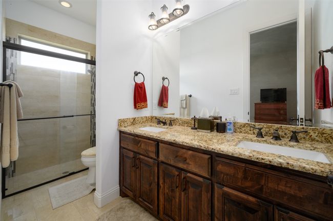 Full bathroom featuring toilet, a sink, double vanity, and a stall shower | Image 22