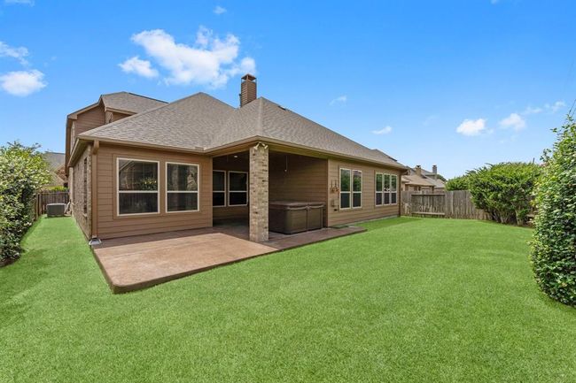 Fully fenced backyard with extended covered patio and hot tub—perfect for relaxing or entertaining | Image 41