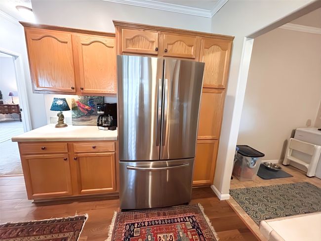 Kitchen featuring dark wood-style flooring, ornamental molding, light countertops, and freestanding refrigerator | Image 18