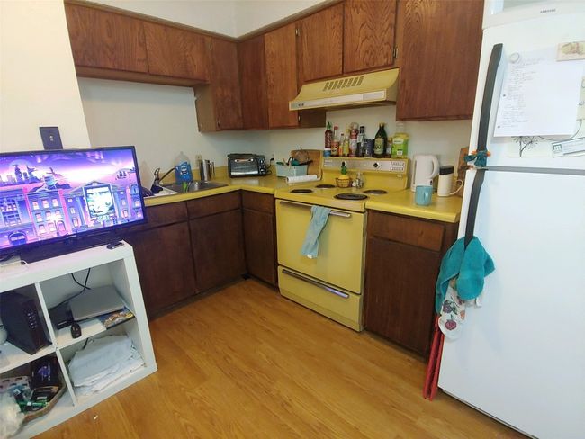 Kitchen with range hood, light countertops, a sink, white appliances, and light wood-style flooring | Image 6