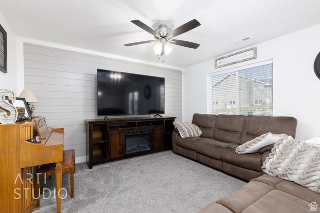 Living room featuring light colored carpet, ceiling fan, wooden walls, and visible vents | Image 11